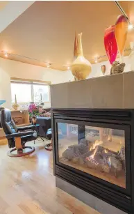  ??  ?? A peninsula-style gas fireplace has glass on three sides and acts as a partial room divider between living, kitchen and dining areas. Floors are solid wood.