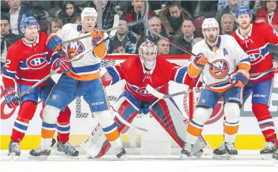  ?? PHOTOS: JOHN MAHONEY ?? Montreal Canadiens goaltender Carey Price tracks the play while flanked by teammates Karl Alzner, left, and Jeff Petry, right, as New York Islanders forwards Jason Chimera, centre left, and Cal Clutterbuc­k, centre right, try to provide screens during...