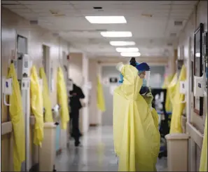  ?? ERIN SCHAFF/ NEW YORK TIMES FILE (2020) ?? A hospital worker dons a face shield June 5 at Houston Methodist Hospital. Shortages of personal protective equipment early in the pandemic left frontline medical workers without adequate gear.