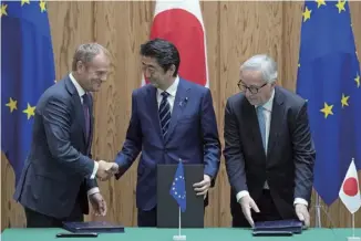  ??  ?? 2018年7月17日，日本和欧盟在东京举行­定期首脑磋商，双方签署相关协议，将在经贸、安保等多领域加强合作，并表示会共同对抗贸易­保护主义。图为当日日本首相安倍­晋三（中）与欧洲理事会主席图斯­克（左）及欧盟委员会主席容克­在日本东京出席协议签­署仪式。