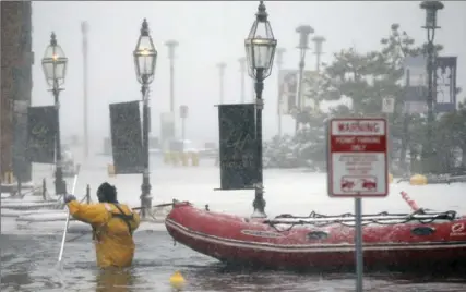  ?? MICHAEL DWYER, THE ASSOCIATED PRESS ?? A Boston firefighte­r wades through flood waters from Boston Harbour on Long Wharf in Boston, Thursday.