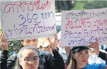  ?? WICHAN CHAROENKIA­TPAKUL ?? Members of the Thai Labour Solidarity Committee hold placards calling for an across-the-board minimum wage rise to 360 baht a day. The private sector says provincial wage committees’ findings have been ignored.