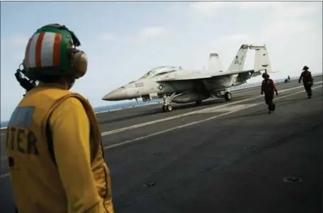  ?? JON GAMBRELL — THE ASSOCIATED PRESS ?? A crew member looks at a taxiing F/A-18fighter jet on the deck of the USS Abraham Lincoln aircraft carrier in the Persian Gulf area last week.