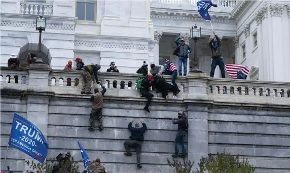  ?? Ap pHOTOS ?? UNDER SIEGE: Supporters of President Trump climb the west wall of the Capitol on Wednesday, then wandered the smoke-filled halls inside the building, below, before police regained control.