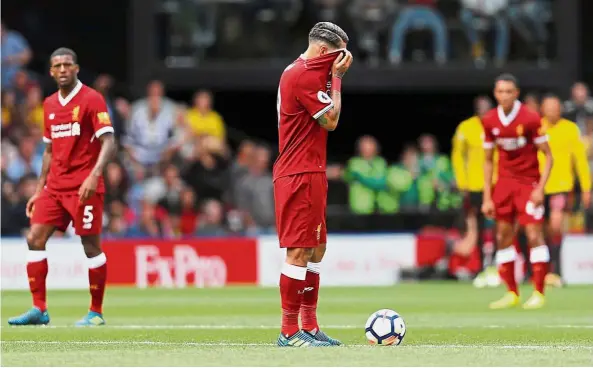  ??  ?? Red-faced: Liverpool’s Roberto Firmino covers his face as he waits to restart the match after they conceded a second goal against Watford at Vicarage Road yesterday. The match ended 3-3. — Reuters