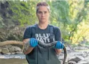  ?? BLUE WATER BALTIMORE ?? Baltimore Harborkeep­er Alice Volpitta holds a dead American eel in September 2021 in the Jones Falls stream.