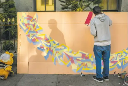  ?? Photos by Santiago Mejia / The Chronicle ?? Jaz Cameron paints on a giant piece of found cardboard near Fifth and Mission streets in San Francisco.