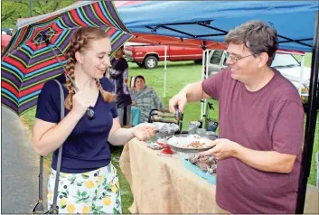  ?? Doug Walker ?? Sarah Cooper, a Berry student from Lafayette, Indiana, samples some of Eric Knutsen’s candied pecans at the Berry Spring Market on Saturday. Knutsen is a sophomore at Shorter University.