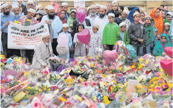  ??  ?? Members of the Muslim community gather yesterday at the floral tributes at St Ann’s Square in Manchester
