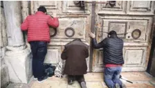 ?? AP ?? Oración. Varios visitantes oran en las puertas cerradas de la Iglesia del Santo Sepulcro, ayer en Jerusalén.