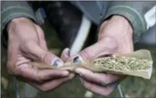  ?? CHRIS YOUNG/THE CANADIAN PRESS VIA AP ?? A man rolls a large joint in a Toronto park on Wednesday, Oct. 17, 2018. Canada became the largest country with a legal national marijuana marketplac­e as sales began early Wednesday.