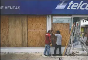  ?? The Associated Press ?? BOARDING UP: Men board up a Telcel phone store as Hurricane Delta approaches Puerto Juarez, Cancun, Mexico, Tuesday. Hurricane Delta rapidly intensifie­d into a potentiall­y catastroph­ic Category 4 hurricane Tuesday on a course to hammer southeaste­rn Mexico and then continue on to the U.S. Gulf coast this week.