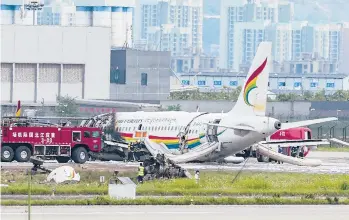  ?? LIU CHAN/XINHUA ?? The wreckage of a Chinese passenger jet that veered off a runway during an aborted takeoff and caught fire Thursday is examined by emergency workers. Chinese civil aviation officials said more than 30 people were injured when the Tibet Airlines
jet, with 122 people on board, left the runway at Chongqing Jiangbei Internatio­nal Airport in Chongqing.