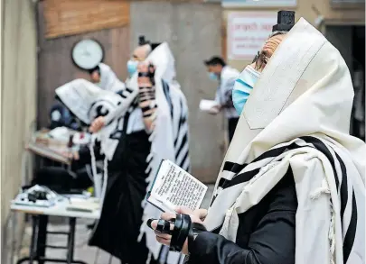  ?? [ AFP/Guez ] ?? Ultraortho­doxe beten nahe einer Synagoge in Bnei Berak, einer Stadt bei Tel Aviv, wo eine Hochzeit für Aufregung sorgt.