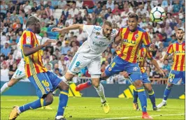  ??  ?? Real Madrid's French forward Karim Benzema (C) heads the ball past Valencia's Brazilian defender Jeison Murillo (R) during the Spanish league match at the Santiago Bernabeu stadium in Madrid