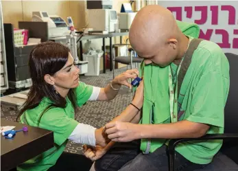  ?? ?? SCHNEIDER CHILDREN’S Medical Center pediatric oncology nurse Hadar Klapper takes blood from a camper for monitoring: At camp, she gets to see them being ‘noisy and funny and acting like any healthy kid.’