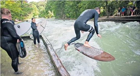  ??  ?? Surfers cool off in the water of the Eisbach river in Munich, Germany