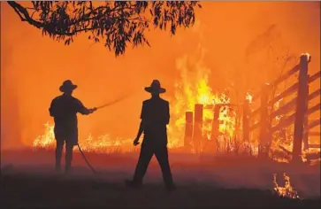  ?? Peter Parks AFP/Getty Images ?? RESIDENTS TRY to defend a property from a brush fire in Hillsville, Australia, about 200 miles north of Sydney. Authoritie­s warned most people in the fires’ paths to shelter in place, as it was too late to flee.