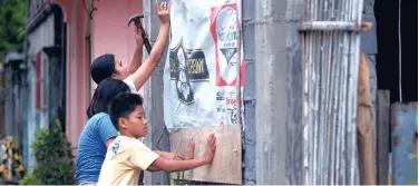  ?? Associated Press ?? ↑
Residents reinforce their house as they prepare for a coming typhoon in Legazpi, Philippine­s, on Monday.