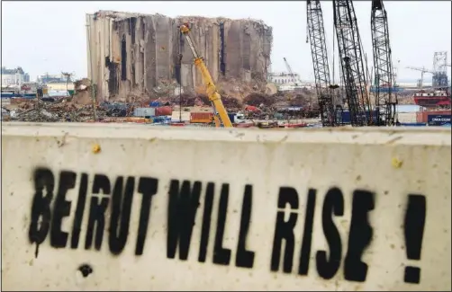  ?? (AP/Hussein Malla) ?? A slogan is painted on a barrier Dec. 2 in front of towering grain silos gutted in the massive August 2020 explosion at the Beirut seaport in Lebanon.