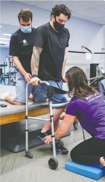  ?? JEFF MCINTOSH / THE CANADIAN PRESS ?? Humboldt Broncos bus crash survivor Ryan Straschnit­zki is helped to
stand in a walker by Eric Daigle, left, and Jill Mack while he attends a recent physiother­apy session in Calgary.