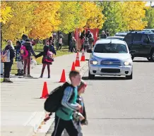  ?? GAVIN YOUNG ?? Parents line up in vehicles to pick up students at New Brighton Elementary School. Traffic congestion ‘continues to be an issue’ at many Calgary schools despite a ticketing blitz by the city.