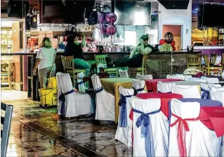  ?? PHOTOS BY MELANIE BELL / THE PALM BEACH POST ?? A cleaning crew sits inside the La Isla Del Encanto nightclub on Sunday, hours after one person was shot dead and three others were wounded.