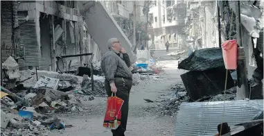  ?? AFP/ GETTY IMAGES ?? A resident of Homs, Syria looks at a damaged building after returning to the city Friday. The last rebels left Homs under a deal that hands the government a symbolic victory.