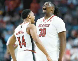  ?? TIM NWACHUKWU/GETTY ?? North Carolina State’s Casey Morsell, left, and DJ Burns Jr. celebrate during a second-round game against Oakland on Saturday. The Wolfpack are the lowest seed of the four ACC teams in the Sweet 16 at No. 11.