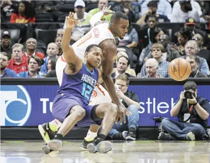  ??  ?? ATLANTA: Charlotte Hornets guard Treveon Graham (12) and Atlanta Hawks forward Paul Millsap (4) vie for a loose ball during the first half of an NBA basketball game, Tuesday, in Atlanta. — AFP