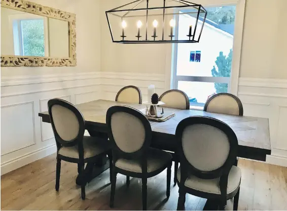  ??  ?? The mirror in the dining room is from HomeSense and was used as part of the couple’s wedding decoration­s when they married in August 2019. The five-pendant chandelier is from Home Depot, while the dining table is from The Brick and the chairs from Structube. Nathan added the panelling in the dining room, which adds to the classic feel of the room.