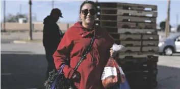  ?? ELIZABETH MAYORAL CORPUS PHOTO ?? Calexico resident Azucena Wendz smiles as she holds her bags filled with fresh produce from the IVFB pop-up distributi­on at Imperial Valley Mall on Friday, January 6, in El Centro.