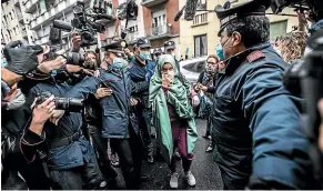  ?? AP ?? Silvia Romano, escorted by police, arrives at her home in Milan wearing a face mask to guard against Covid-19.