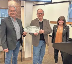  ?? MIKE KRAMER/PEKIN DAILY TIMES ?? Pekin Outreach Initiative board member Gary Davis, left, and president Greg Ranney, center, admire a $75,000 novelty check presented by Pekin Mayor Mary Burress.