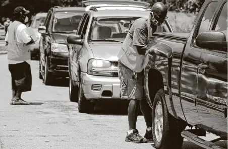  ?? Jay Reeves / Associated Press ?? Volunteers load boxes of fruit and produce into vehicles at a site where free food was being distribute­d to residents of Alabama’s Black Belt region in Selma. Relief groups are trying to provide aid during the pandemic in the historical­ly poor region.