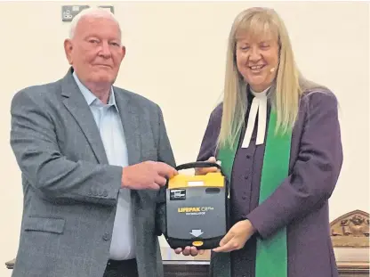  ??  ?? Stewart Davidson hands the defibrilla­tor to the Rev Barbara Ann Sweetin of East and Old Church.