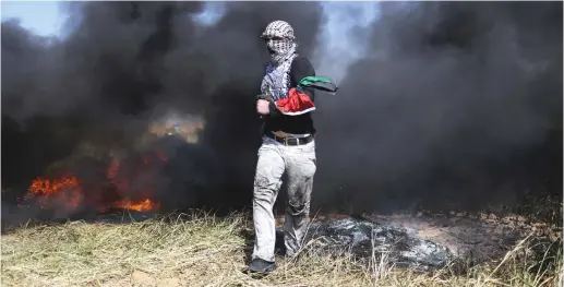  ?? (Reuters) ?? A PALESTINIA­N runs through smoke during clashes along the Gaza border.