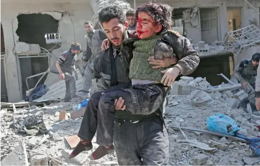  ?? AFP ?? Syrians rescue a child following a reported regime air strike in the rebel-held town of Hamouria in the besieged Eastern Ghouta region on Wednesday. —
