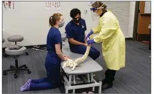  ?? (Special to the Democrat-Gazette) ?? Dr. Amy Suessle, an assistant professor at the New York Institute of Technology College of Osteopathi­c Medicine at Arkansas State University, dons full personal protective equipment as she instructs second-year medical students Erica Hochstein and Syed Hasnain on the Jonesboro campus.