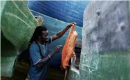  ?? PHOTO: REUTERS ?? Mohamed Fane, a migrant from Senegal who journeyed by wooden boat to the Spanish island of Gran Canaria, looks at a life jacket from one of several abandoned boats in Arinaga.