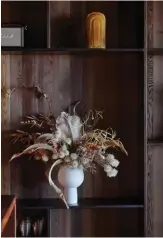  ??  ?? LEFT In the kitchen, open shelving crafted from stained birch ply functions as storage and display. This floral arrangemen­t is by
On My Hand in a vase from Paper Plane. BELOW The back benchtop is stainless steel that rises up to meet the stained cedar that forms the splashback and the rangehood shrouded in black steel. The fridge and pantry are integrated in birch ply cabinetry on either side of the stove, matching the ceiling, while the island teams kwila with stained birch ply cupboard fronts. The Osso stools are by Mattiazzi from Simon James, the Muffins lamp in the adjacent living area is by Brokis from ECC and on the right is a ladder-like Verso Shelf by Hem from Tim Webber Design.