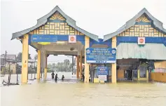  ??  ?? The flood at Rantau Panjang tax-free zone entrance. — Bernama photo