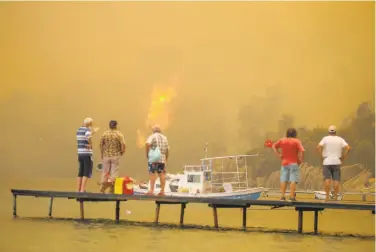  ?? Emre Tazegul / Associated Press ?? Tourists wait to be evacuated by boat from the smokeengul­fed Mazi area as a wildfire burns near the shore in Bodrum, Turkey. A heat wave across southern Europe has intensifie­d scores of wildfires.