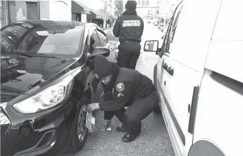  ?? The Pew Charitable Trusts/TNS ?? ■ Cpl. Tiffany Chambers of the Baltimore transporta­tion department clamps a self-release parking boot on a car on a downtown street in January. Her colleague, Officer Myisha Denman, fills out the paperwork. Baltimore is one of about two dozen cities and counties that use the high-tech boots.