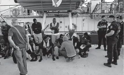  ?? Anaelle Le Boudec, Afp/getty Images ?? Police round up migrants on the Sea-watch 3 charity ship Saturday in the Italian port of Lampedusa, Sicily. The ship’s German captain, Carola Rackete, below, was arrested after maneuverin­g the ship into port without permission and ramming a police vessel. Rackete, 31, has commanded a handful of rescue missions for the Sea-watch group.