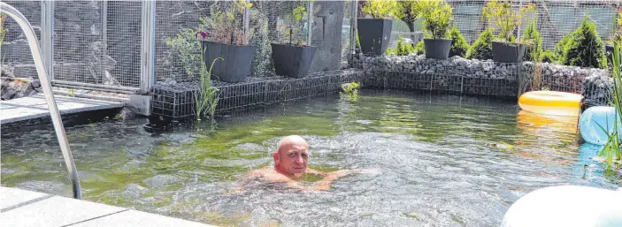  ?? FOTO: REGINA BRAUNGART ?? Harald Niemann in seinem Schwimmtei­ch in der Mittagspau­se. Die Flachwasse­rbereiche schließen sich links und rechts an.