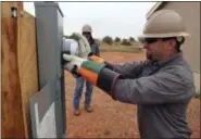  ?? FELICIA FONSECA — THE ASSOCIATED PRESS ?? Ken Wagner, a journeyman lineman with Piqua Power System in Piqua, Ohio, installs an electric meter at a home in Kaibeto, Arizona, on the Navajo Nation, as his co-worker, Kevin Grinstead, looks on earlier this month.