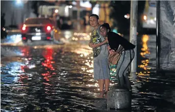  ?? /MAURO PIMENTEL/ AFP ?? People look to see if a bus is coming at the Voluntario­s da Patria Street bus station, in the Botafogo neighbourh­ood, after strong rains flooded multiple areas of the city of Rio de Janeiro in Brazil.