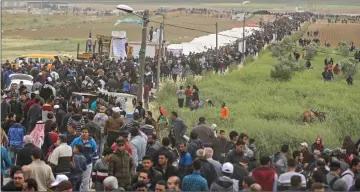  ??  ?? Palestinia­ns marching past a tent city erected along the border with Israel east of Gaza City in the Gaza strip to commemorat­e Land Day. — AFP photos