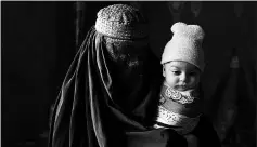  ??  ?? A woman holds her child in Shiga, in eastern Afghanista­n. Members of five families there had lived as unregister­ed refugees near Peshawar, Pakistan, for 30 years.